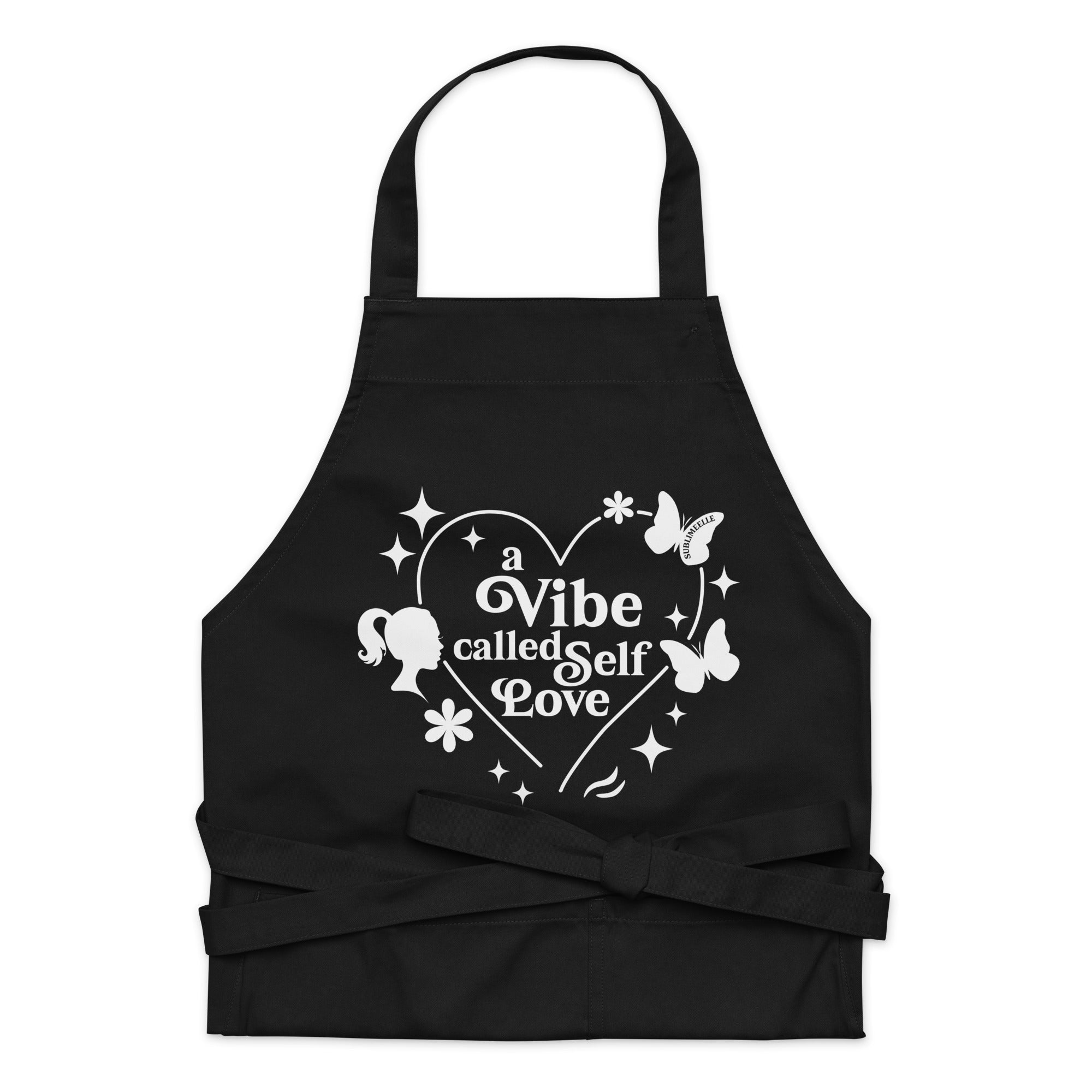 Front view of black apron with quote and design ‘A Vibe Called Self-Love,’ tied strings, stylish and inspirational kitchen wear– “A Vibe Called Self Love” Inspirational Quote - SublimeElle Self - Love