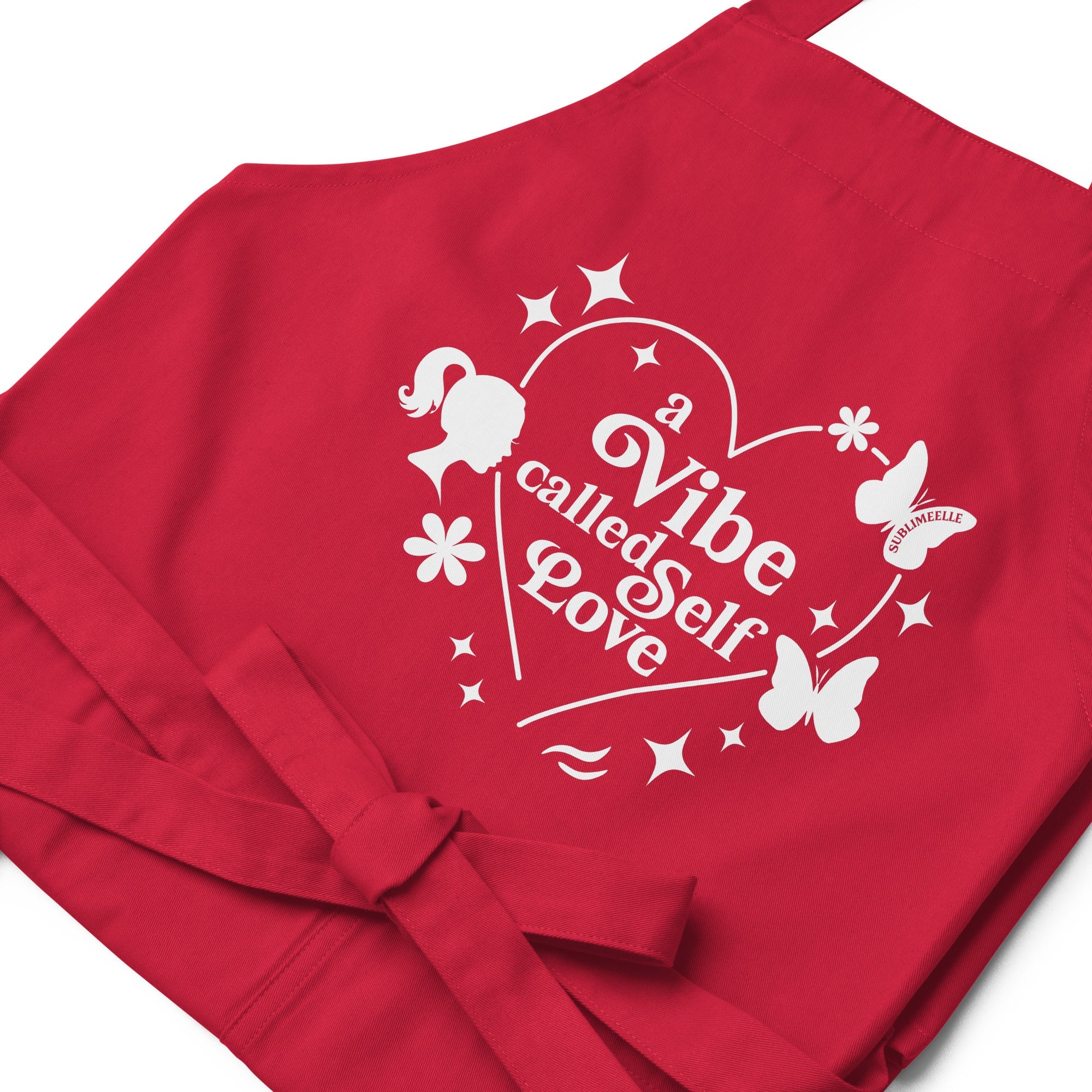 Front view of red apron with  close up of quote and design ‘A Vibe Called Self-Love,’ tied strings, stylish and inspirational kitchen wear- SublimeElle Self - Love